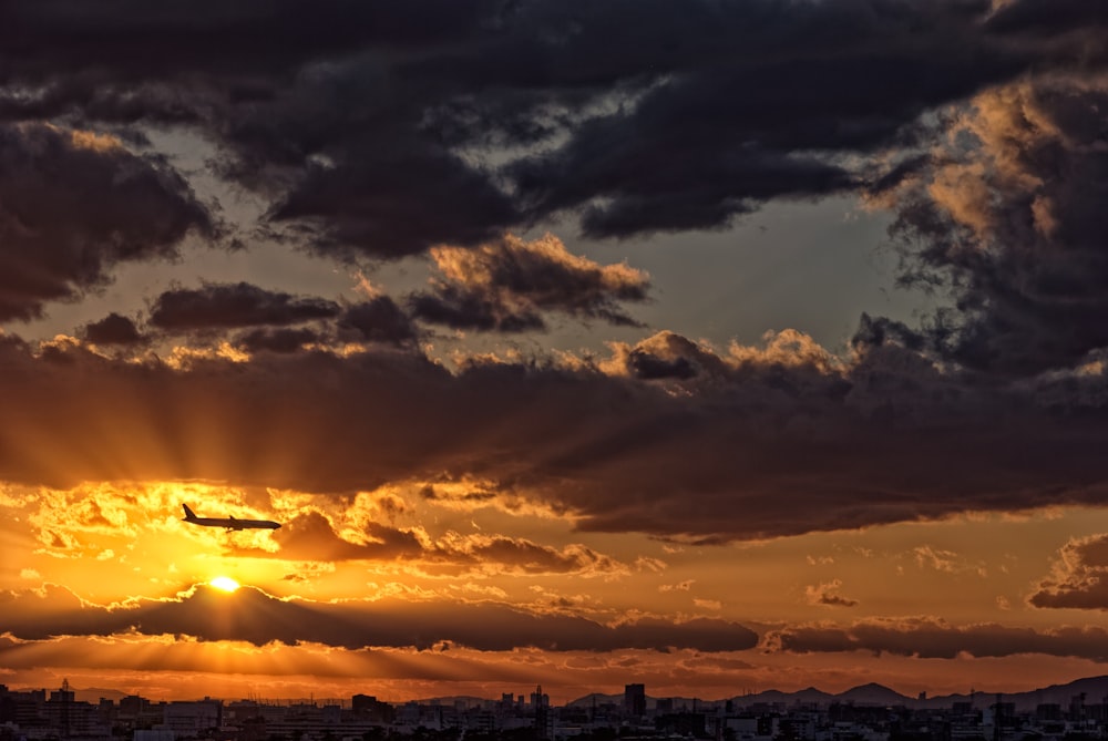 silhouette of buildings under cloudy sky during sunset