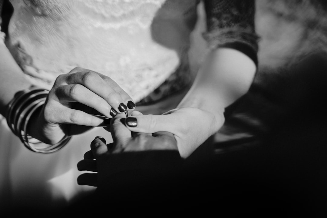 grayscale photo of person holding hand of woman