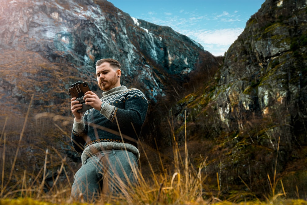 man in black jacket sitting on brown grass field during daytime