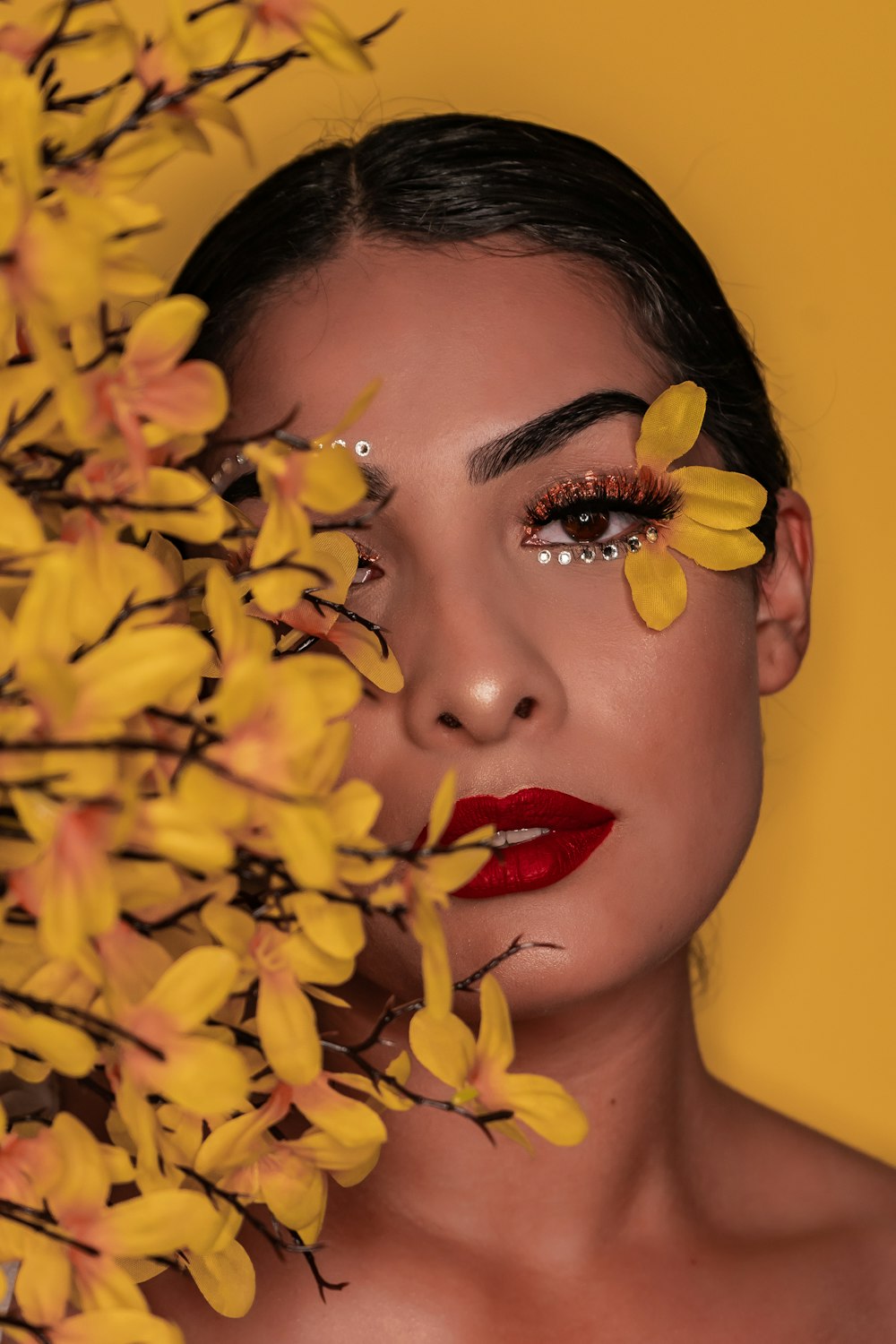 mujer con lápiz labial rojo sosteniendo flor amarilla