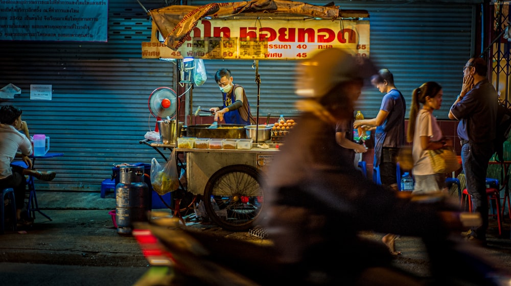 man in blue t-shirt and black pants sitting on brown wooden cart