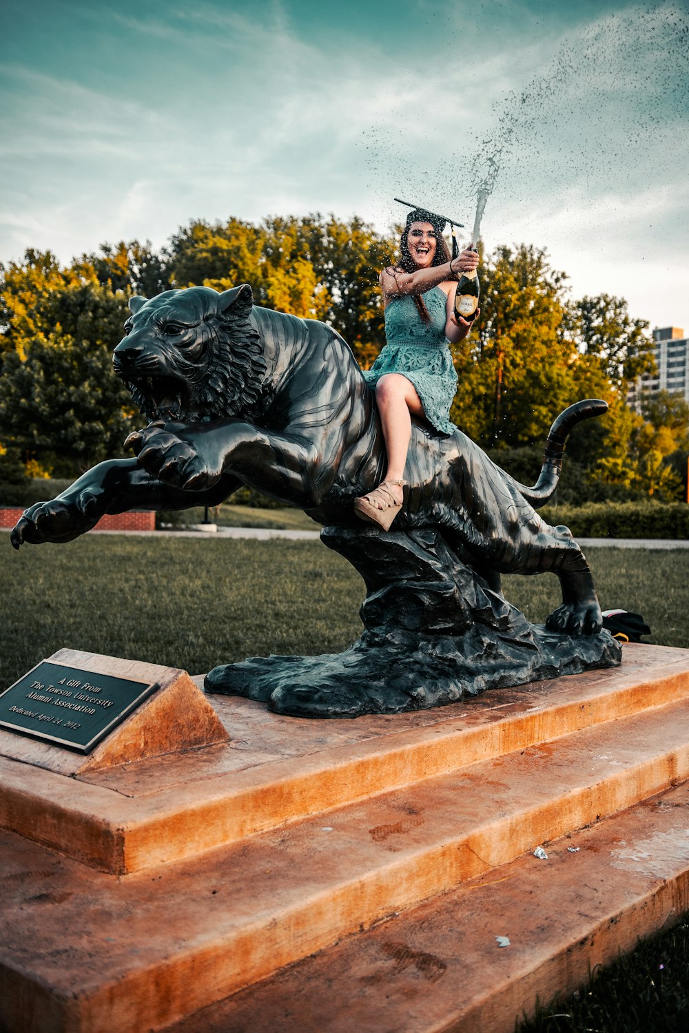 woman in gray t-shirt and black pants sitting on black lion statue