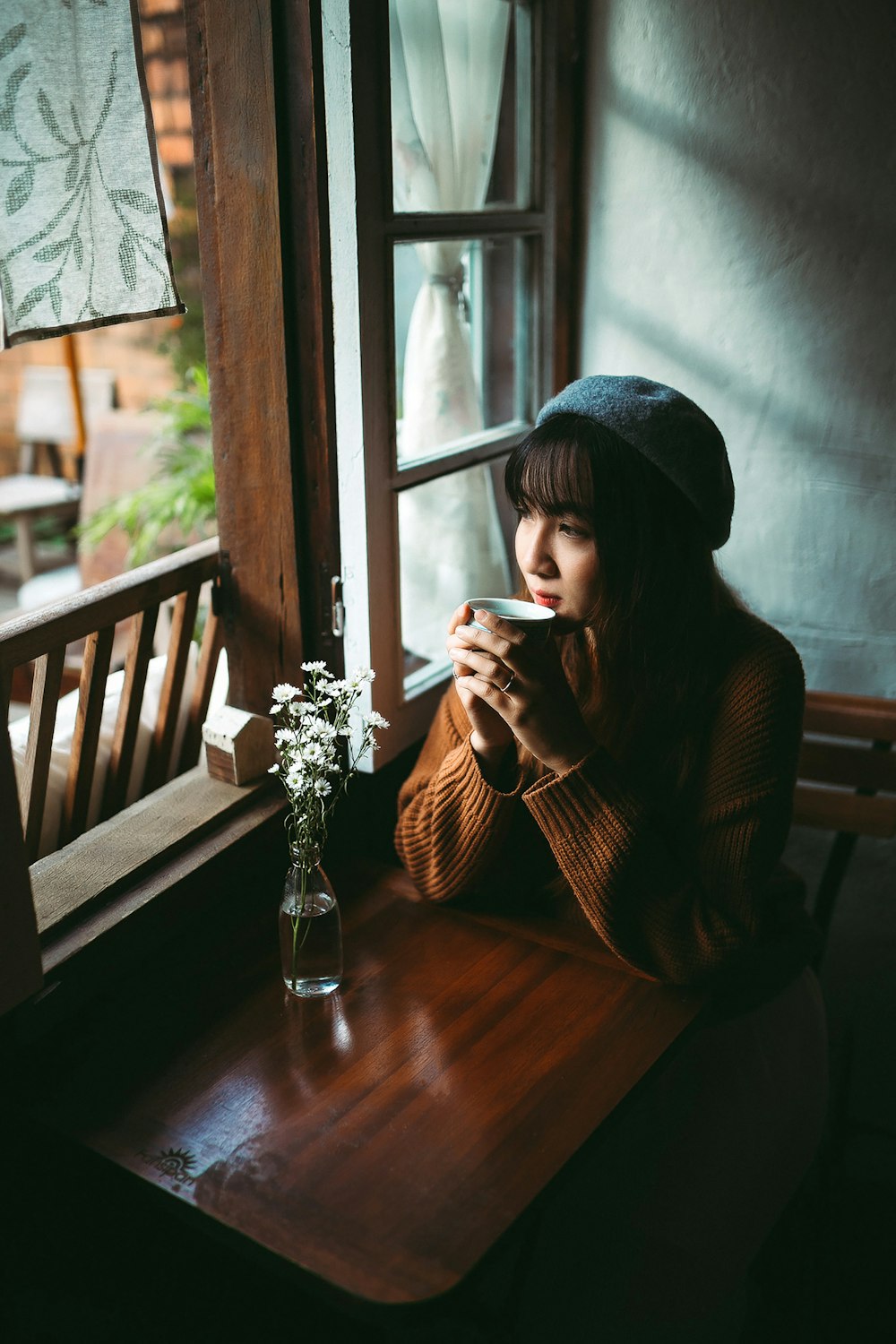 woman in black knit cap sitting on brown wooden chair