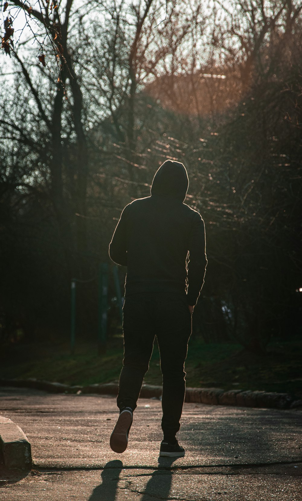 man in black hoodie standing on forest during daytime
