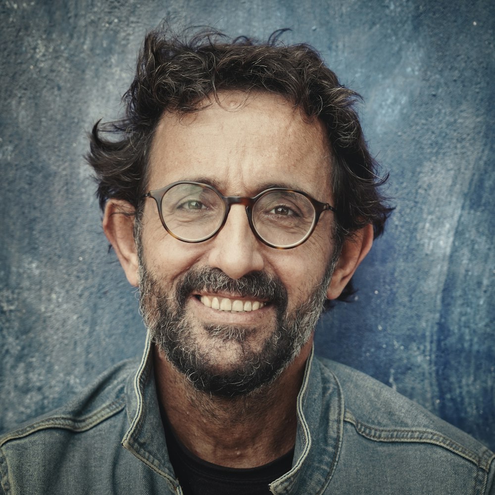 man in gray denim jacket wearing black framed eyeglasses