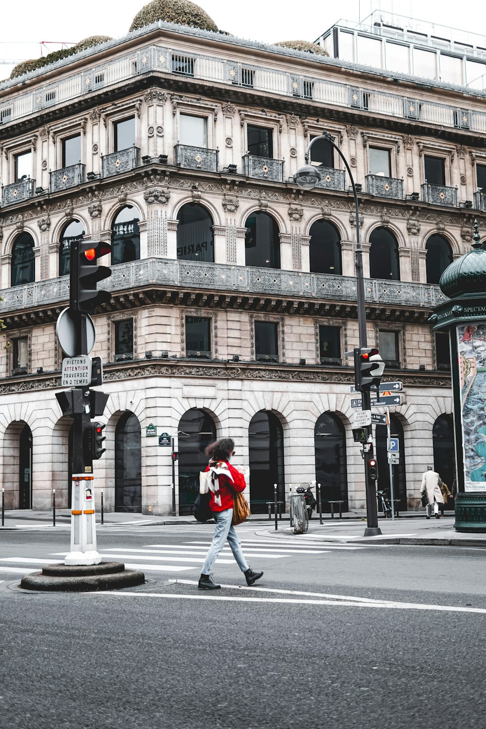 woman in red jacket walking on sidewalk during daytime