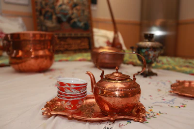 An artfully arranged copper dining set featuring plates, bowls, and cups with intricate detailing.