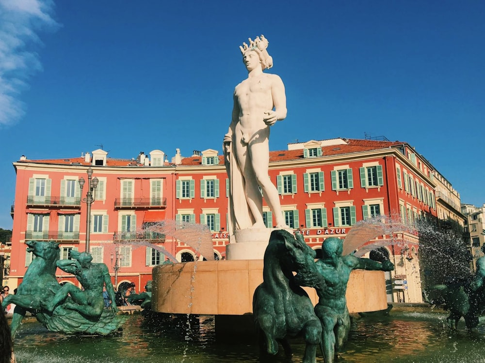 Statua dell'uomo vicino all'edificio marrone durante il giorno