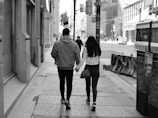 A stylish couple walking hand in hand in a city.