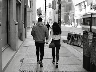 A stylish couple walking hand in hand in a city street.