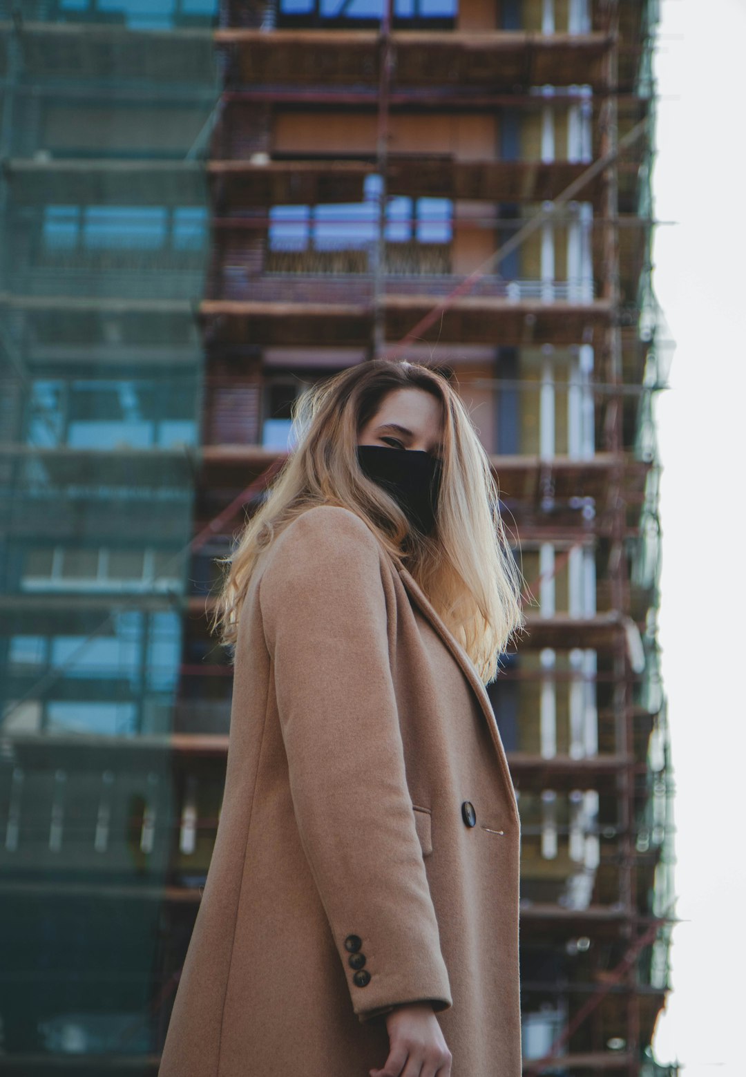 woman in brown coat standing near building during daytime