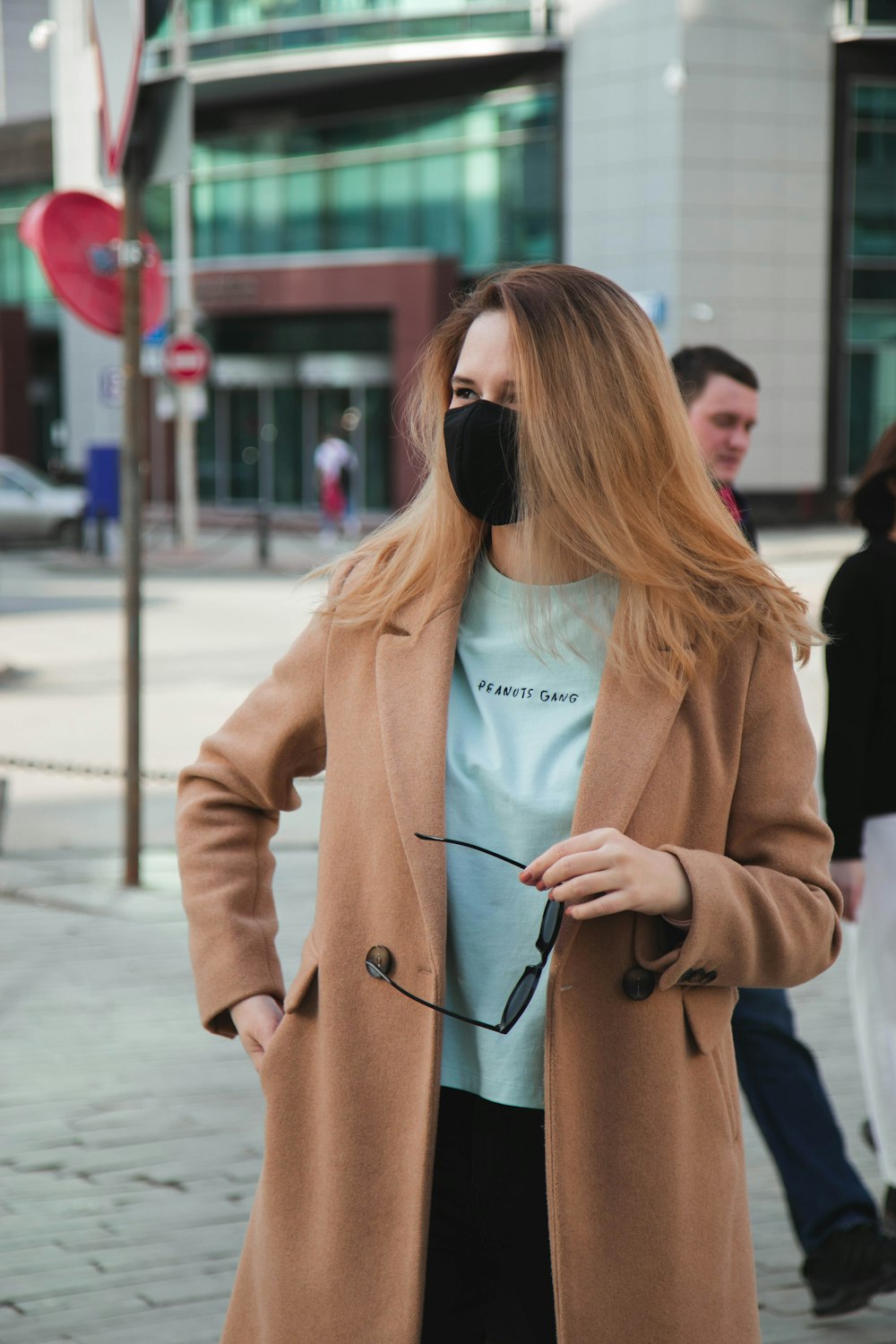 woman in brown coat holding black sunglasses