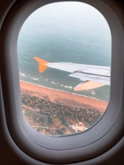 An aircraft being flown over a coastal landscape during relocation.