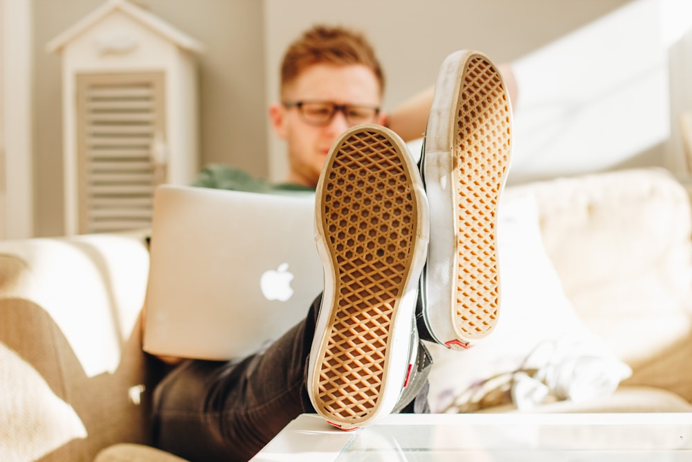 man in black and white sneakers sitting on white couch