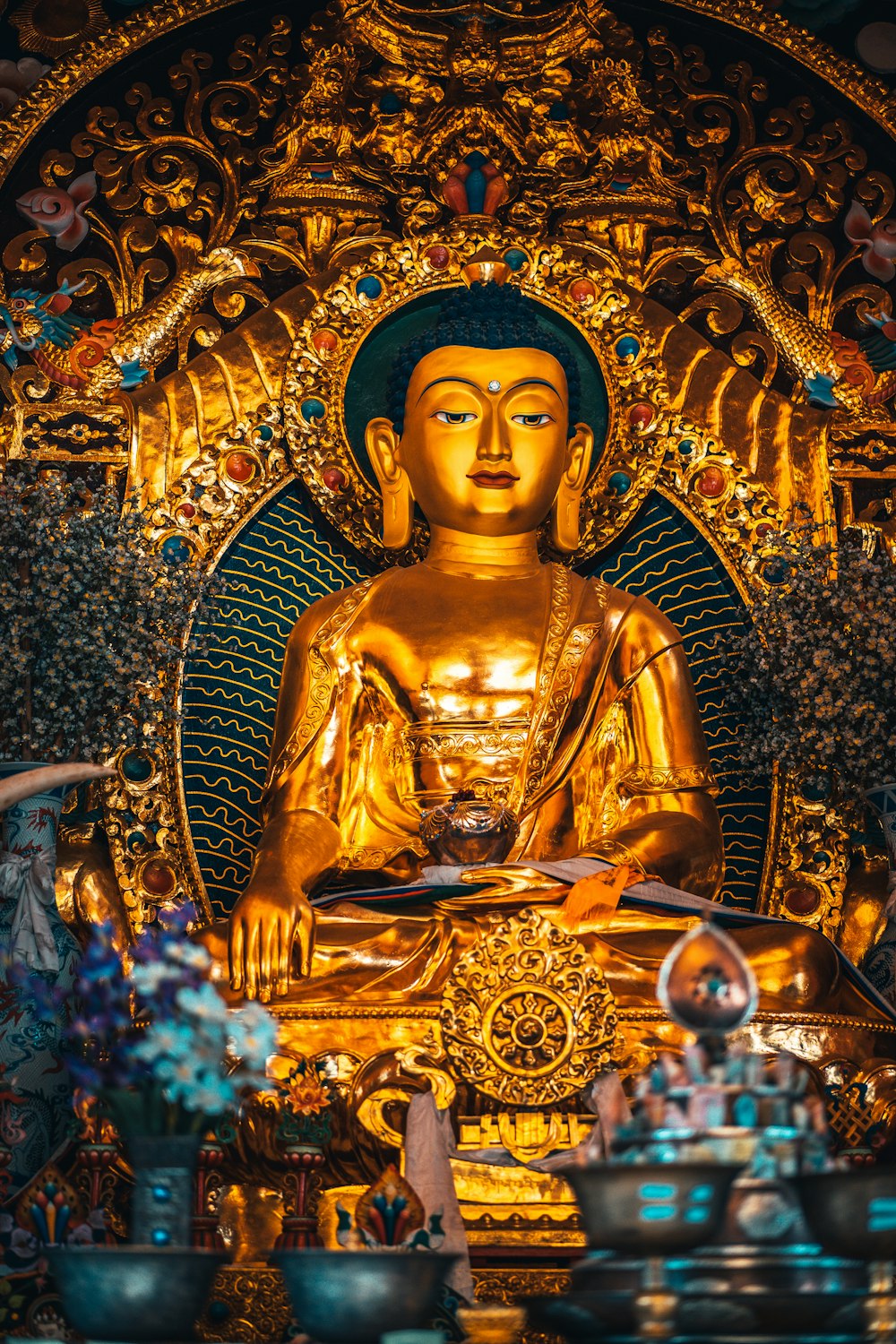 Goldene Buddha-Statue an goldener und blauer Blumenwand