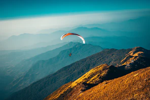 Paraglider soaring over layered mountain ridges, representing solo travel for women Canada and adven