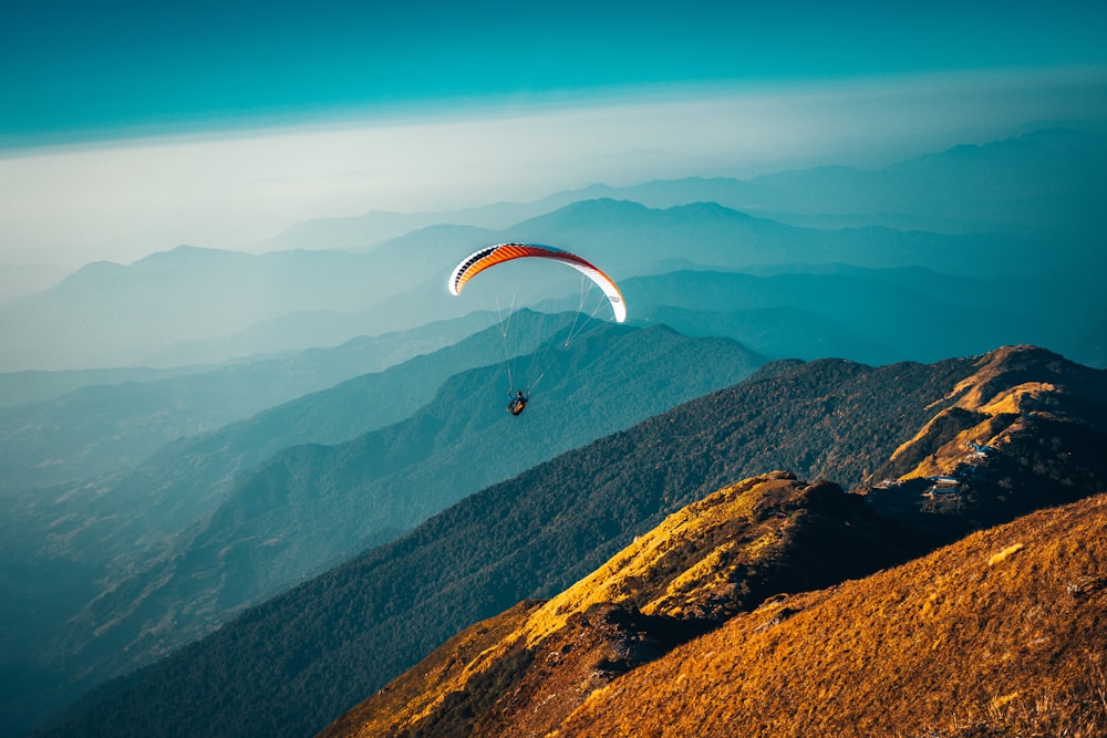 person in parachute over mountains during daytime