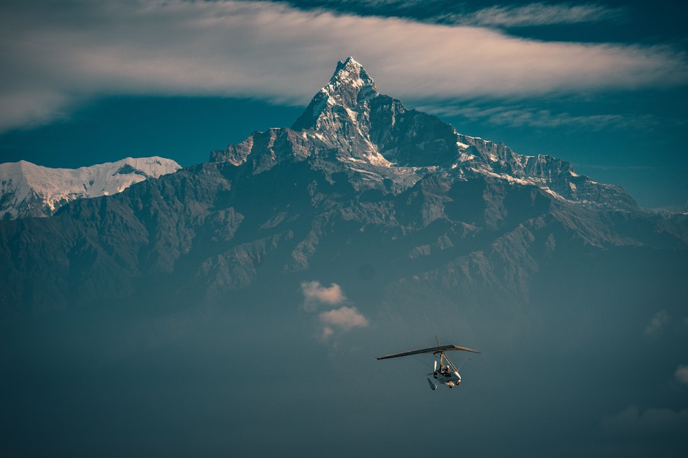 black helicopter flying over snow covered mountain