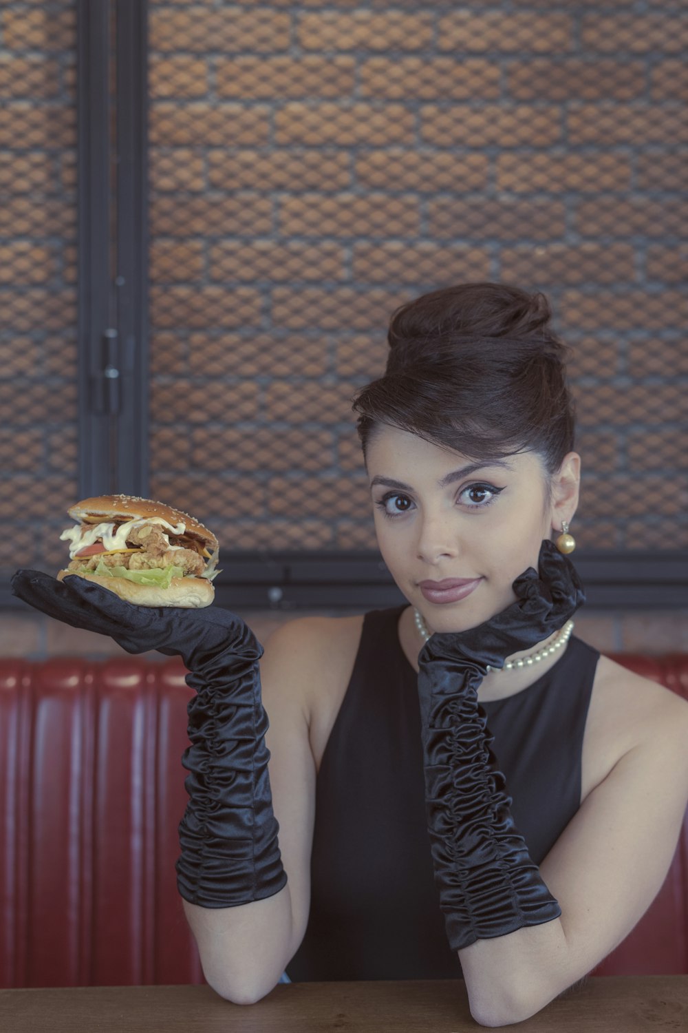 Mujer en top negro sin mangas sosteniendo hamburguesa
