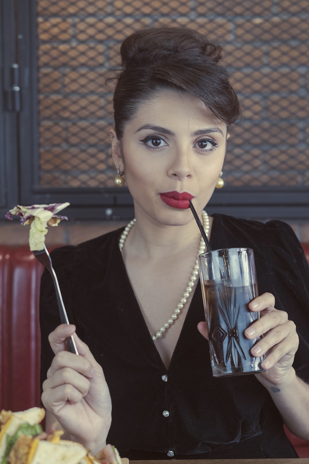 Frau in schwarzem Blazer mit klarem Trinkglas