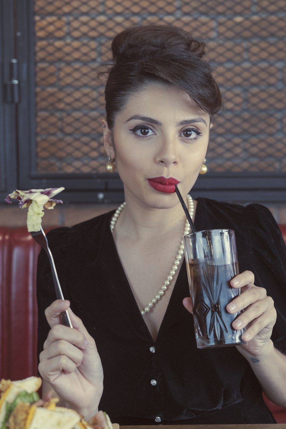 Mujer en blazer negro sosteniendo un vaso transparente