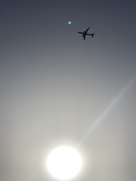 An airplane flying over a clear blue sky during sunrise.