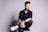 man in black dress shirt and blue denim jeans sitting on black chair
