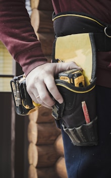 person holding black and yellow hand tool