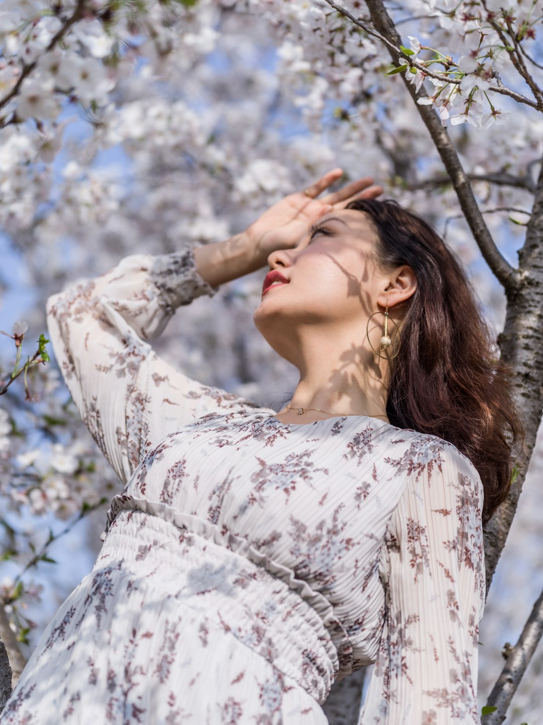 woman in white and black floral long sleeve shirt standing under tree during daytime