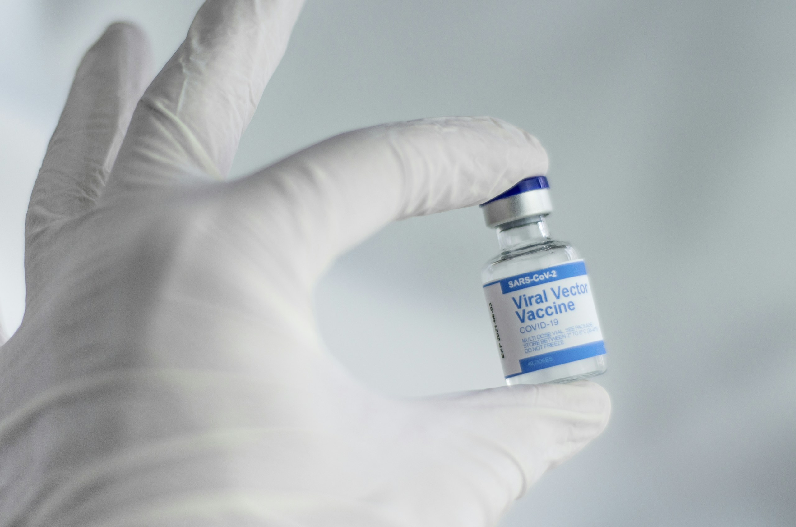 coronavirus vaccines, person holding white and blue labeled bottle AstraZeneca