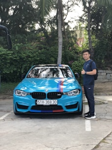 A professional driver standing next to a clean car ready to drive.