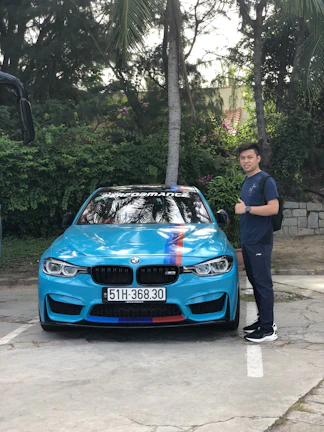 A professional driver standing beside a clean car outside a family home.