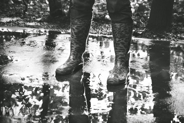 A pair of colorful rubber rain boots standing on a wet city sidewalk.