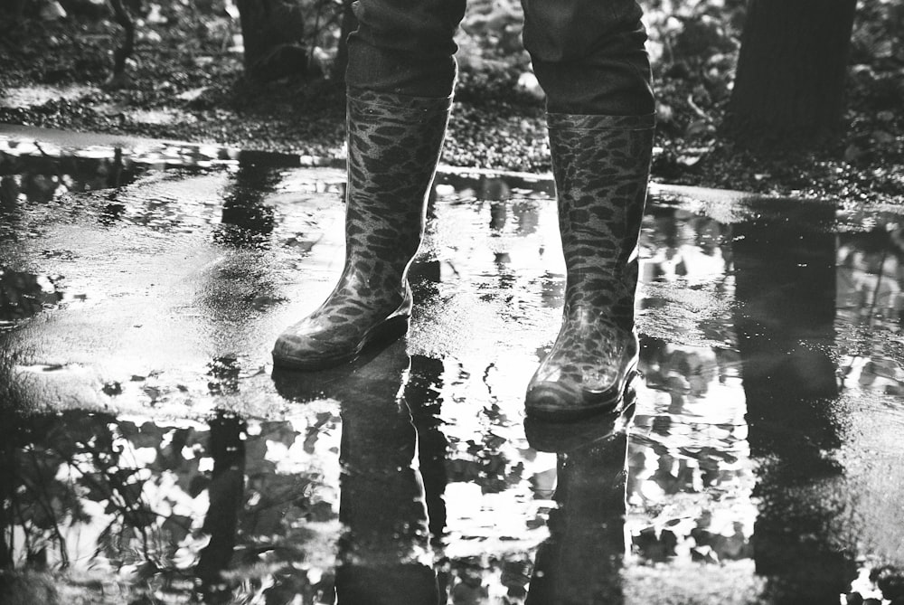 person in black pants and boots standing on water