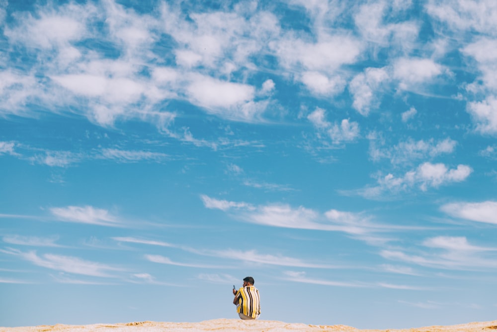 homme et femme marchant sur le sable brun sous le ciel bleu et les nuages blancs pendant la journée