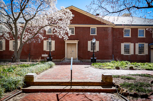 A sunlit historic brick building on South Flower Street with blooming flowers in the foreground.