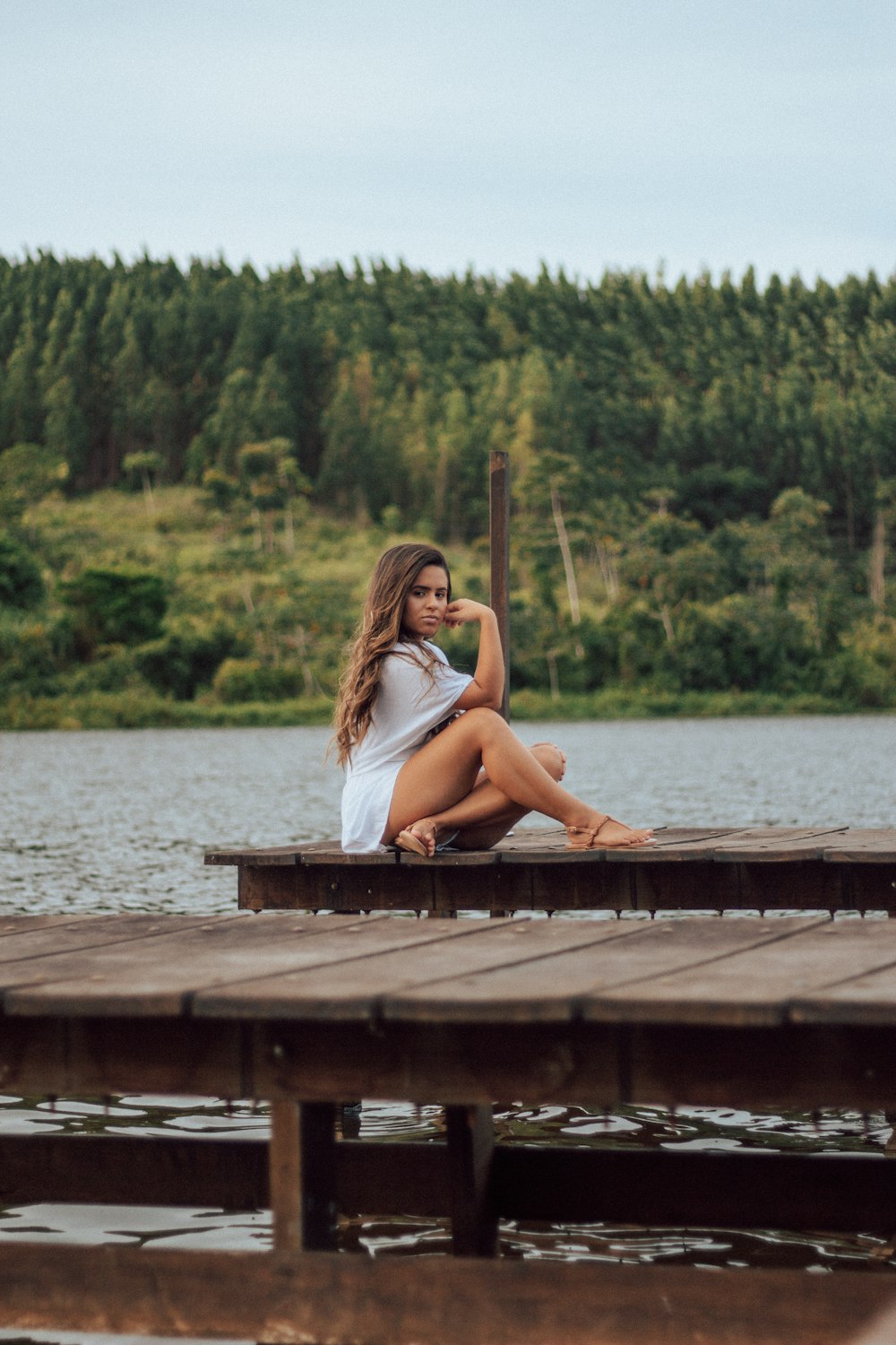 woman in white tank top sitting on brown wooden dock during daytime