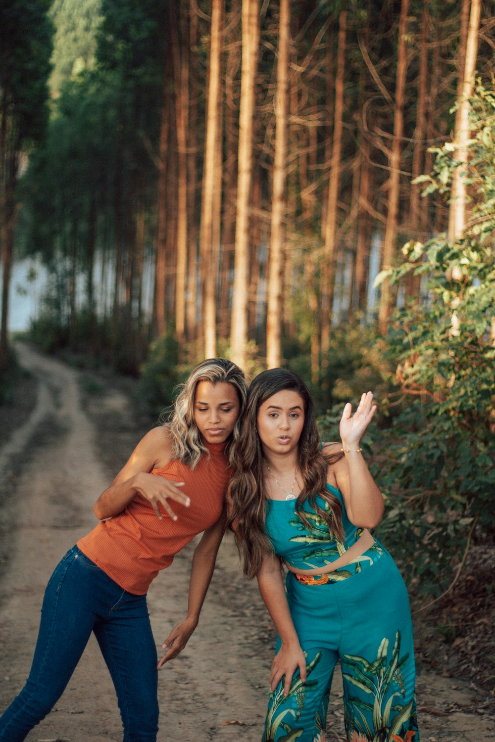 2 women in brown t-shirt standing near trees during daytime