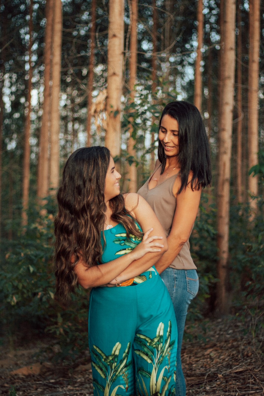 woman in green tank top and blue denim shorts standing beside woman in brown tank top