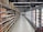 An aisle in a supermarket with shelves on the left displaying a variety of packaged goods, including sauces and snacks. On the right, there is a long row of freezer units containing frozen products. The floor is tiled, and there is bright artificial lighting from overhead.