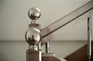 A close-up of a sleek metal staircase with a modern design, set against a workshop background.