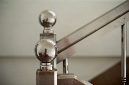 A close-up of a sleek metal staircase with a modern design, set against a workshop background.