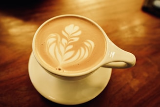 A beautifully arranged coffee cup with latte art on a wooden table.