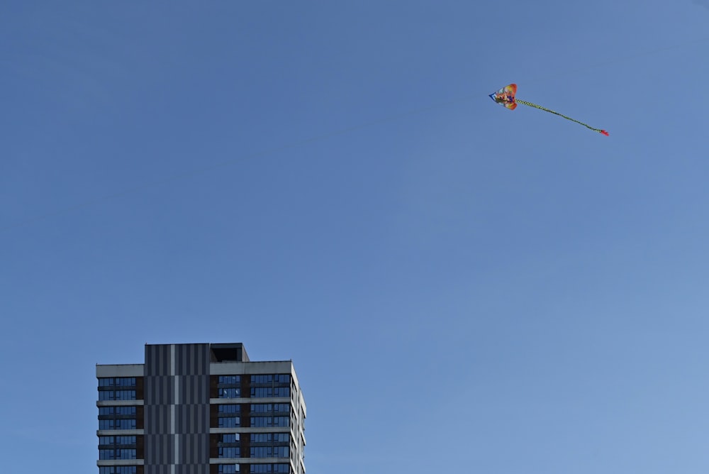 a kite flying in the sky over a tall building