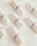 Several white tampons arranged on a soft, white fabric surface. Each tampon is wrapped in individual packaging with a purple band labeled 'TOM'. The arrangement is neat and evenly spaced.