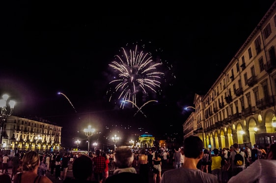A lively crowd celebrating New Year's Eve in Olbia's main square with fireworks lighting up the night sky.