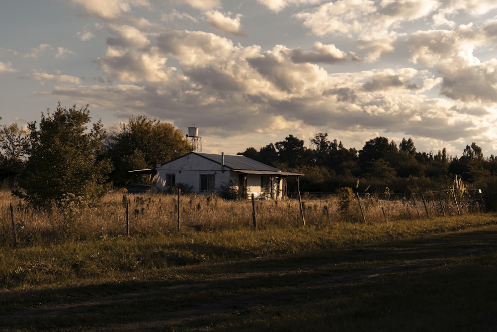 white and black house near green trees under cloudy sky during daytime