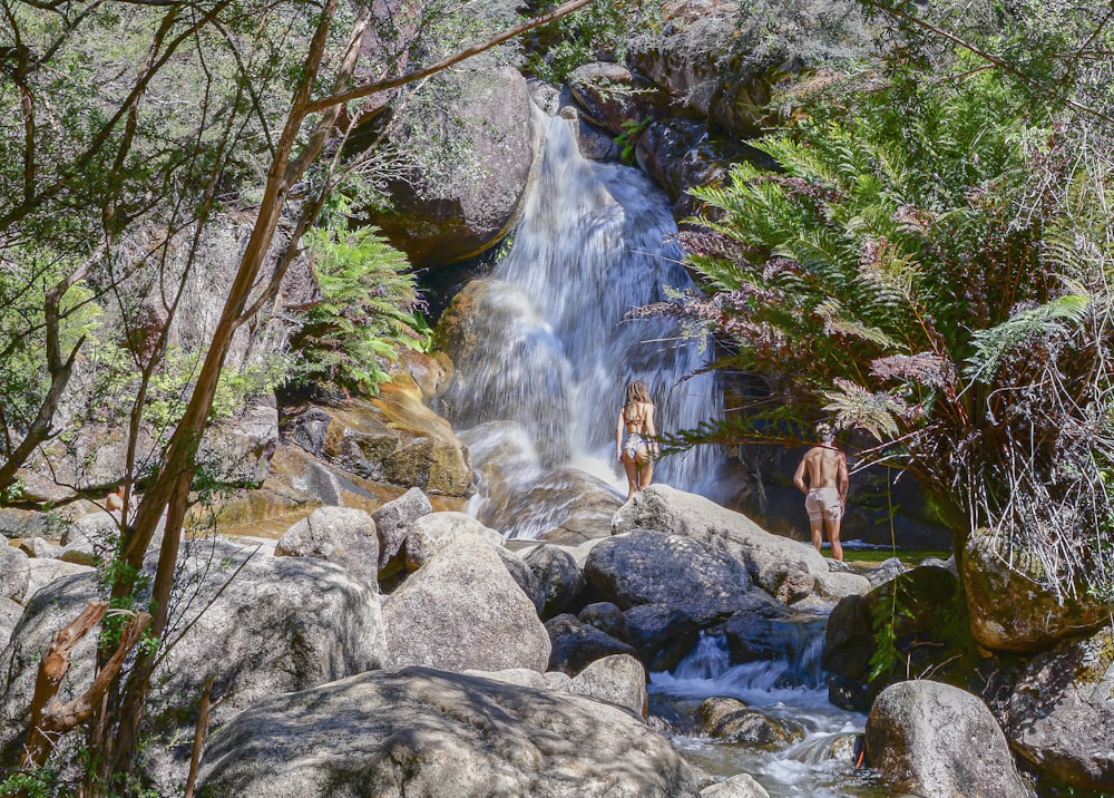 people standing on rocky river during daytime