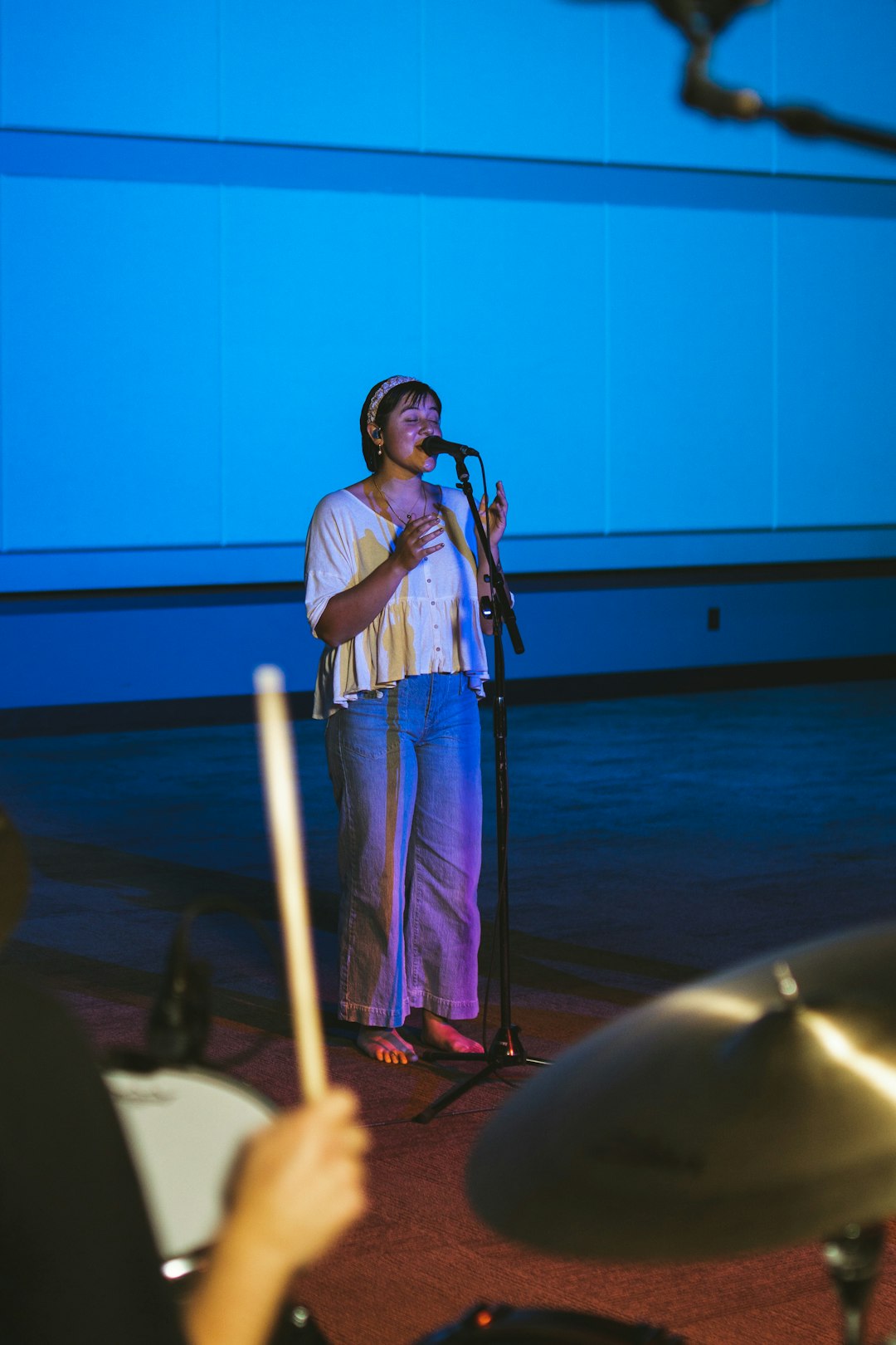 woman in white and blue dress singing on stage