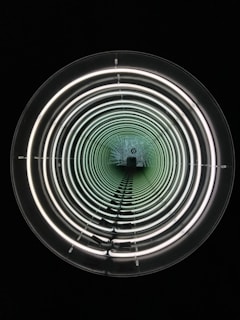 A series of concentric circles of light create a tunnel-like illusion in a dark environment. The circular lights appear to decrease in size, creating a sense of depth and infinity.